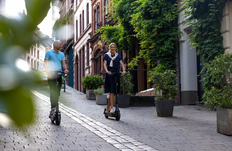 Zwei Personen auf ePF-2 Elektrorollern unterwegs durch die Innenstadt – kompakte E-Scooter mit Straßenzulassung für flexible, umweltfreundliche Mikromobilität im urbanen Raum