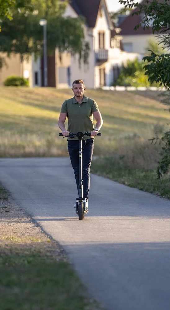 eScooter Reichweite Leistung Mann fährt auf einer Landstraße mit einem leistungsstarken Elektroroller – hohe Akku-Reichweite für lange Touren und starke Motorleistung für ausgedehnte Elektromobilität.