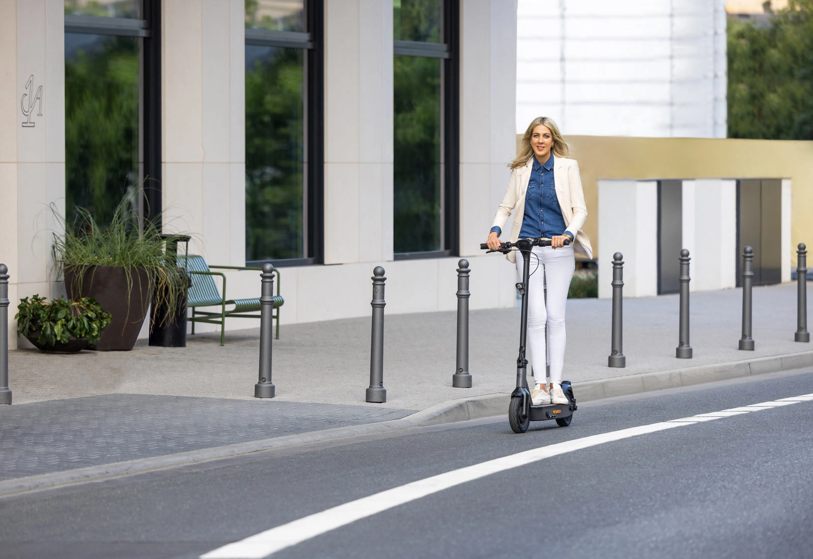 Fahrerin auf dem ePF-2 Elektroroller vor modernem Gebäudekomplex – eleganter E-Scooter mit Straßenzulassung für stilvolle und nachhaltige Mobilität in der Stadt