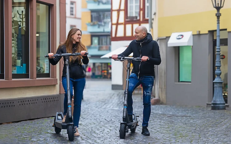 Zwei Fahrer auf ePF PULSE + Elektrorollern in der Stadt – klappbare E-Scooter mit Straßenzulassung, perfekt für nachhaltige Mobilität, urbane Mikromobilität und Pendler im Alltag