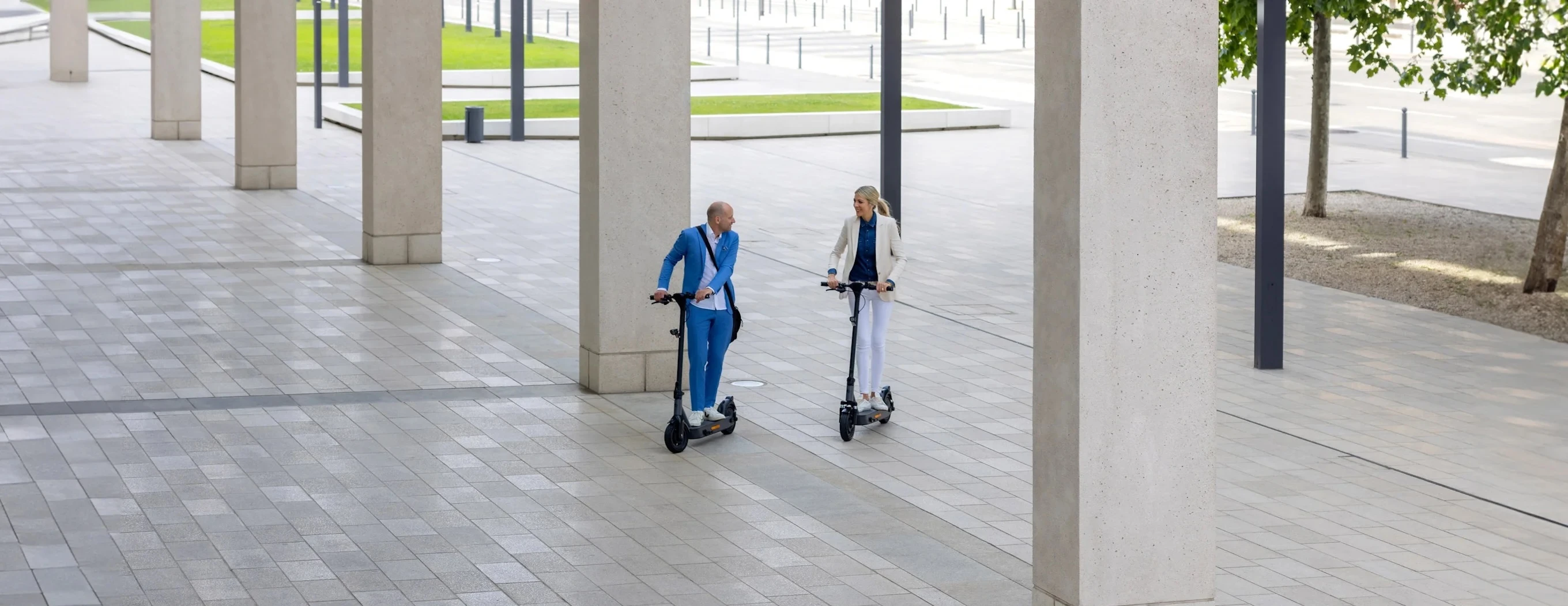 e-scooter fahren gepaeck Zwei Pendler auf kompakten Elektrorollern nutzen im urbanen Umfeld nachhaltige Mikromobilität und Elektromobilität in der Stadt.
