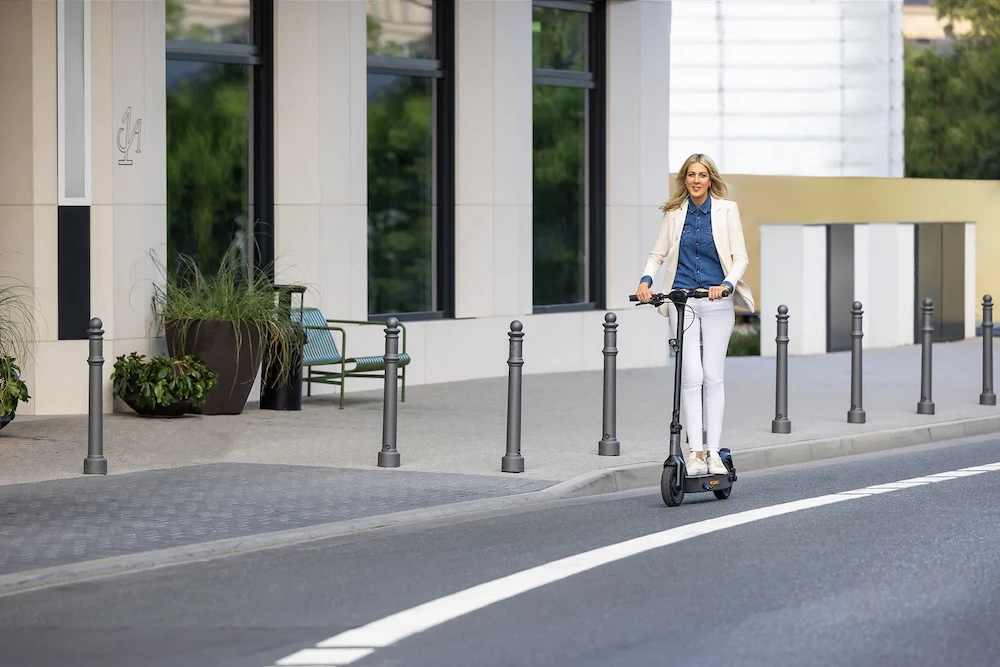 e-scooter Regeln Gesetze Geschäftsfrau fährt einen rechtlich zugelassenen Elektroroller im öffentlichen Straßenverkehrund erfüllt Führerschein- und Versicherungspflichten