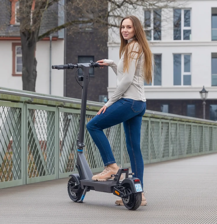 Fahrerin auf dem ePF PULSE + Elektroroller unterwegs auf Brücke – klappbarer E-Scooter mit Straßenzulassung, perfekt für sichere und nachhaltige Mobilität im urbanen Verkehr