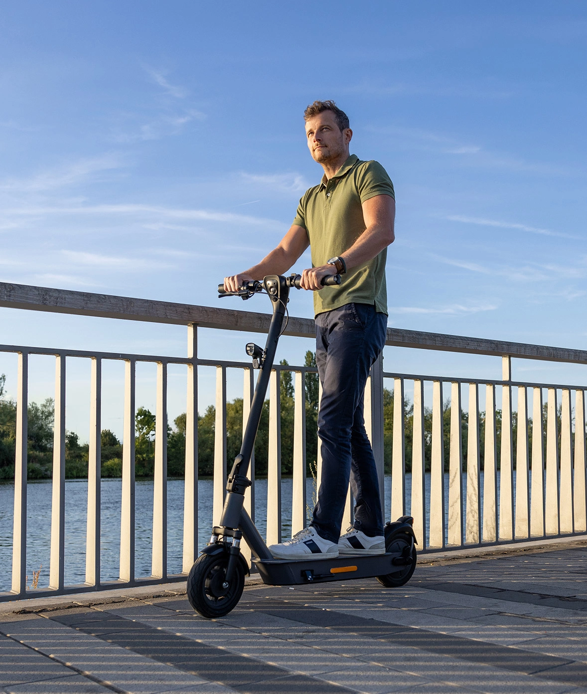 Mann fährt mit dem ePF-2 Elektroroller bei Sonnenschein über eine Brücke – leichter E-Scooter mit Straßenzulassung für komfortable, nachhaltige Mobilität im Alltag