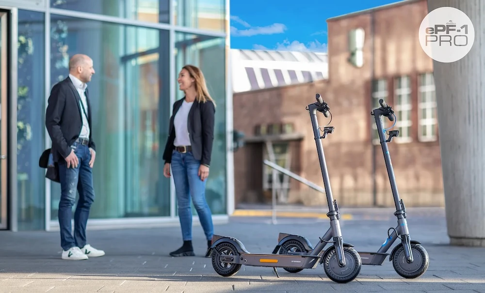 e-scooter modelle Zwei Elektro-Scooter-Modelle – ein klappbarer e-Scooter und die leistungsstarke ePF-1 Pro Variante – stehen vor einem modernen Bürogebäude und symbolisieren nachhaltige Elektromobilität und Mikromobilität.